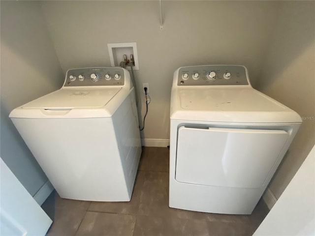 washroom featuring dark tile flooring, washing machine and clothes dryer, and hookup for a washing machine