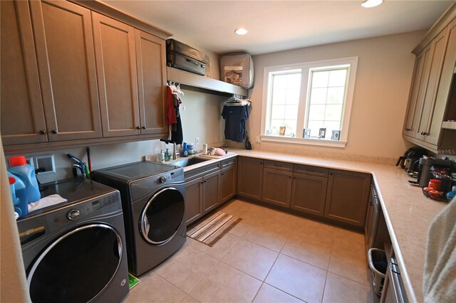 washroom with cabinets, sink, light tile flooring, and washing machine and clothes dryer