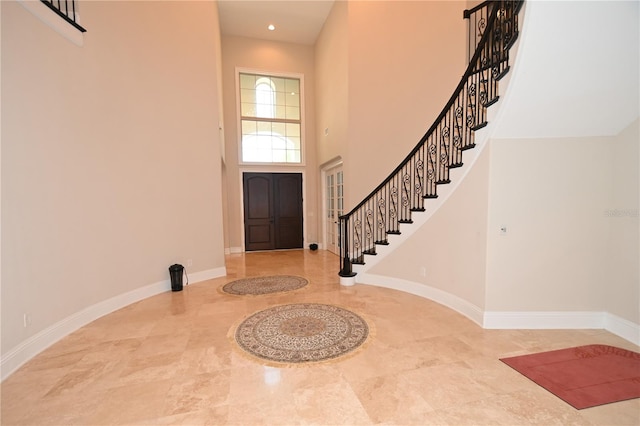 entrance foyer featuring a towering ceiling and light tile flooring