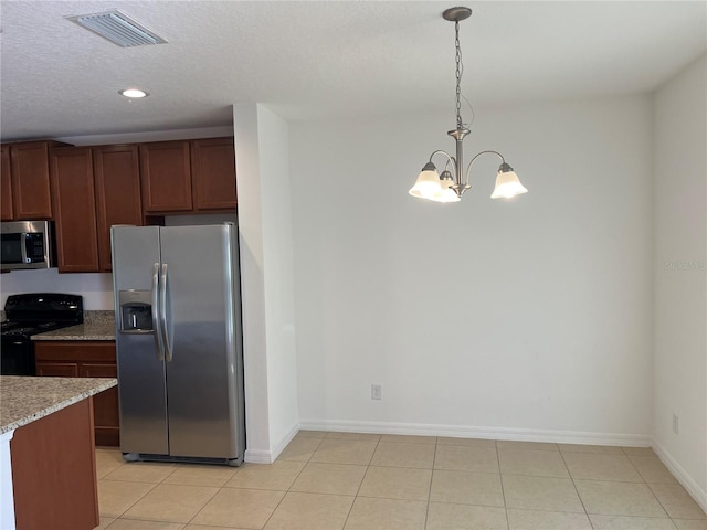 kitchen with appliances with stainless steel finishes, hanging light fixtures, an inviting chandelier, and light tile flooring