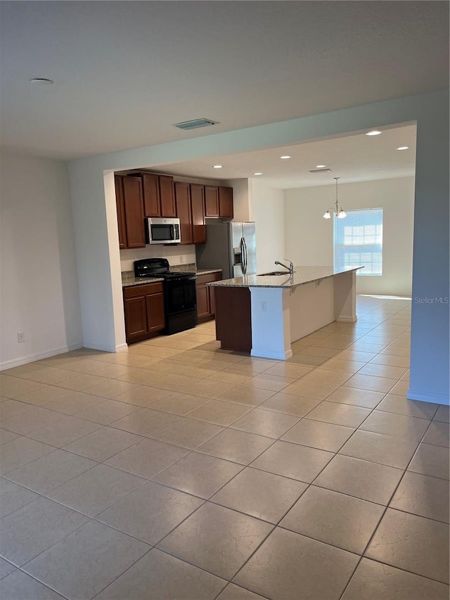 kitchen with appliances with stainless steel finishes, hanging light fixtures, light tile floors, sink, and a center island with sink