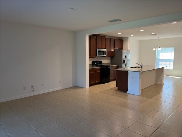 kitchen featuring light stone countertops, an inviting chandelier, an island with sink, stainless steel appliances, and pendant lighting