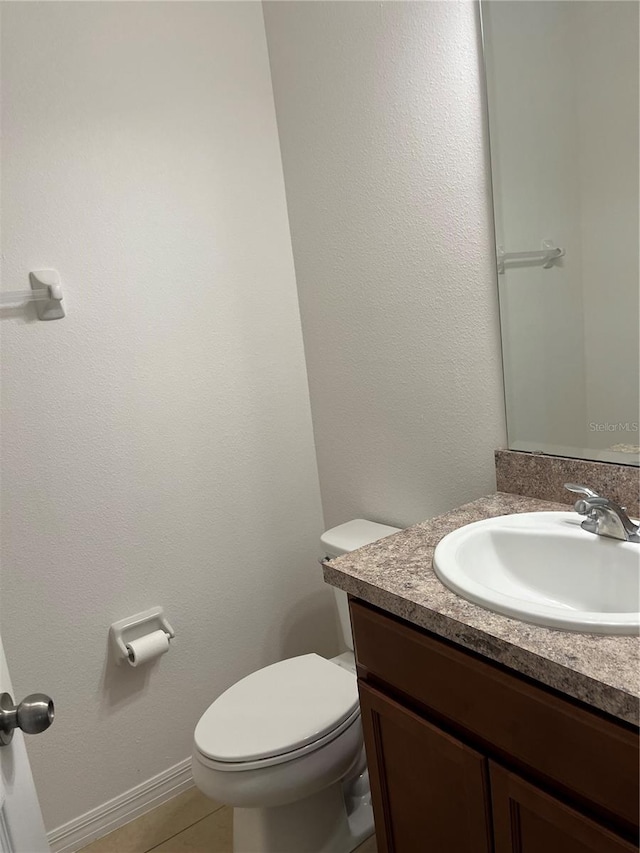 bathroom with toilet, tile flooring, and vanity