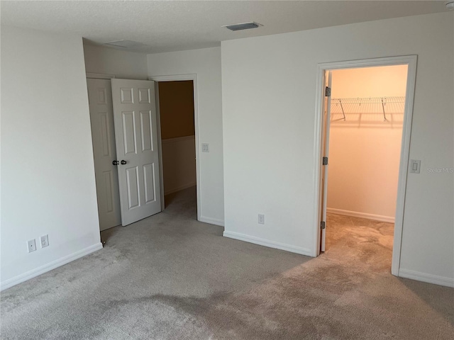 unfurnished bedroom featuring a spacious closet, light carpet, and a closet