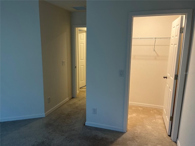 unfurnished bedroom featuring a closet, a walk in closet, and dark colored carpet