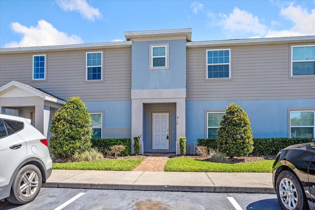 multi unit property with stucco siding and uncovered parking