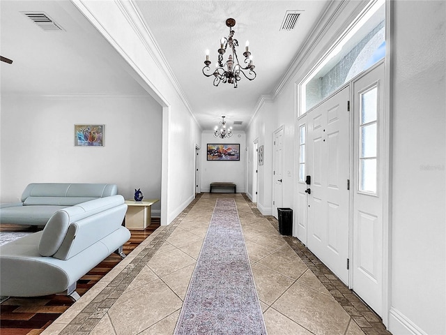 foyer entrance with tile patterned flooring, an inviting chandelier, and crown molding