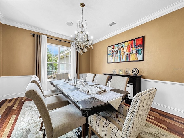 dining area with crown molding, a notable chandelier, and hardwood / wood-style flooring