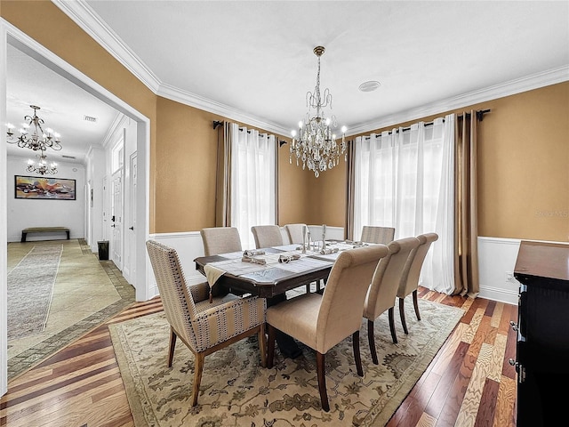 dining space featuring hardwood / wood-style flooring, crown molding, and an inviting chandelier