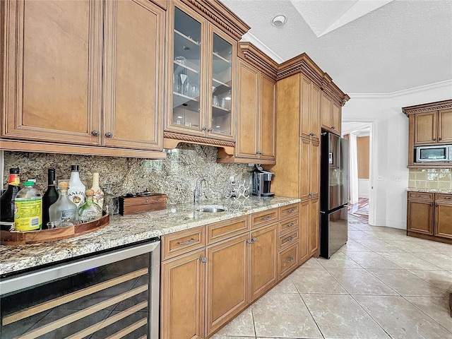 kitchen with light tile patterned floors, a textured ceiling, ornamental molding, stainless steel appliances, and beverage cooler