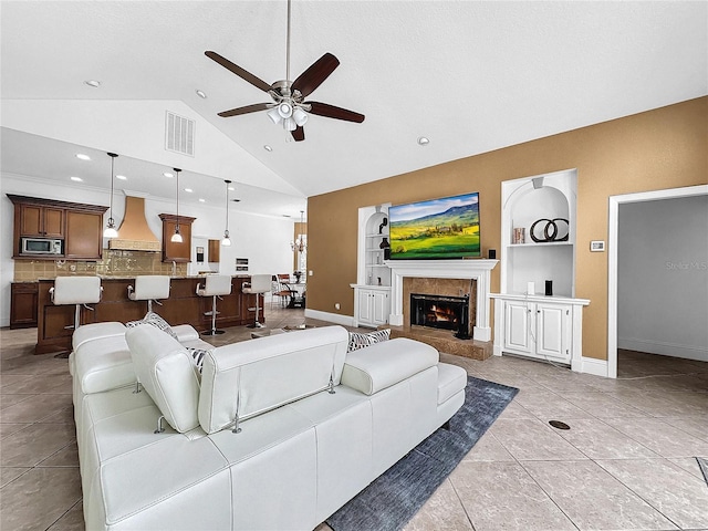 tiled living room featuring ceiling fan, built in features, a high end fireplace, and high vaulted ceiling