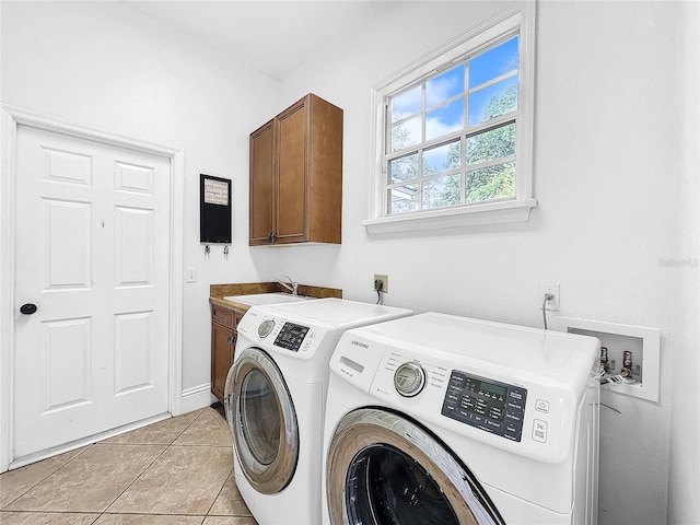 washroom featuring washing machine and dryer, sink, light tile patterned floors, and cabinets