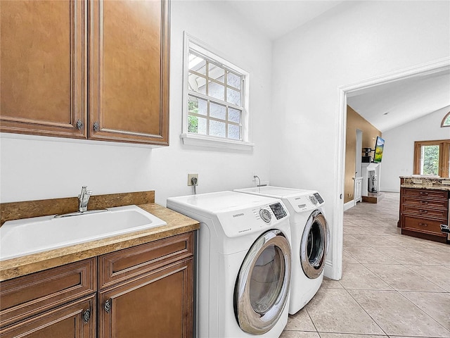 clothes washing area featuring washer and dryer, sink, light tile patterned flooring, and cabinets