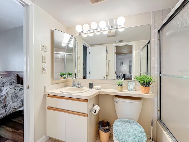 full bathroom with bath / shower combo with glass door, toilet, and vanity