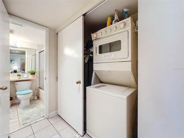 clothes washing area with light tile floors and stacked washing maching and dryer