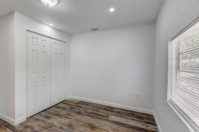 unfurnished bedroom with a textured ceiling, a closet, and dark hardwood / wood-style flooring