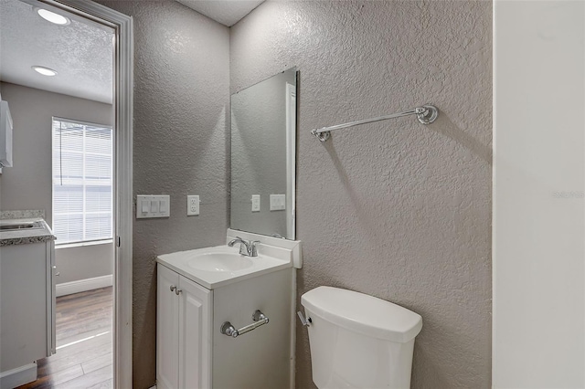 bathroom featuring a wealth of natural light, vanity, toilet, and hardwood / wood-style flooring