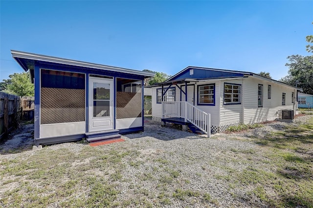 rear view of property featuring central air condition unit, a yard, and a sunroom