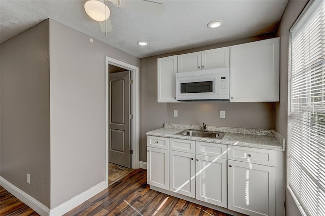 kitchen featuring white cabinets, sink, dark wood-type flooring, ceiling fan, and a textured ceiling