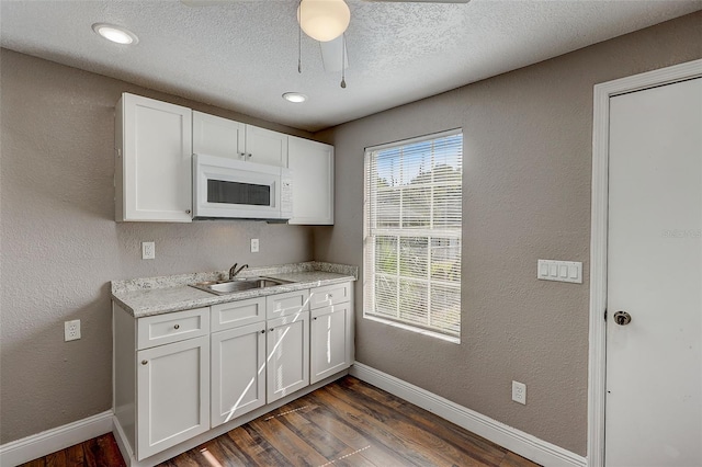 kitchen with dark wood-type flooring, white cabinetry, sink, and a textured ceiling