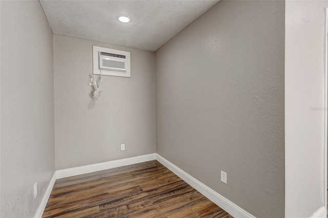 empty room featuring a textured ceiling, hardwood / wood-style flooring, and an AC wall unit