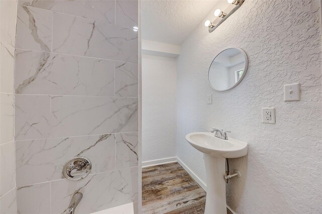 bathroom with hardwood / wood-style floors, tiled shower, and a textured ceiling