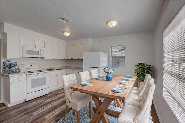 kitchen with white cabinets, white appliances, dark hardwood / wood-style flooring, ornamental molding, and a textured ceiling