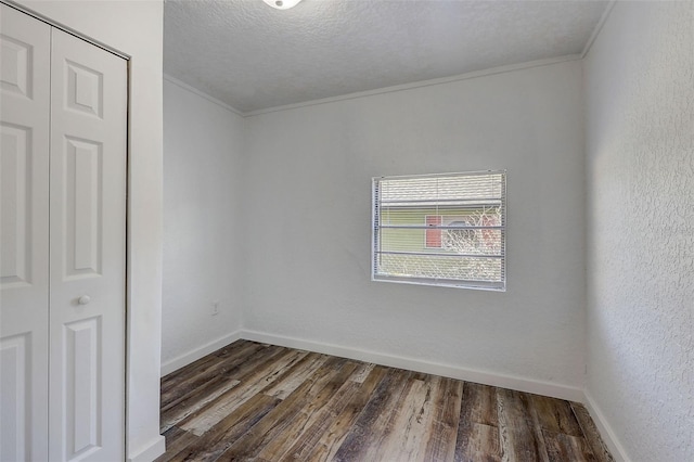 spare room featuring a textured ceiling, ornamental molding, and dark hardwood / wood-style floors