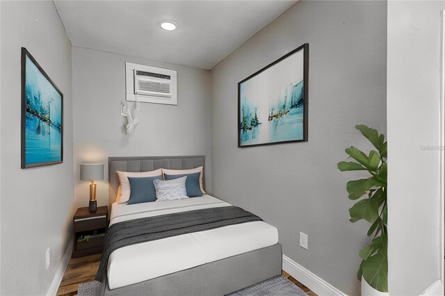 bedroom with hardwood / wood-style flooring and a wall unit AC