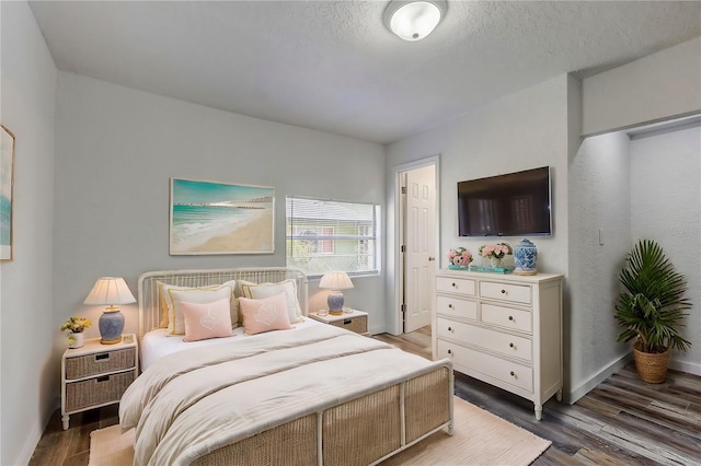 bedroom featuring a textured ceiling and dark hardwood / wood-style floors