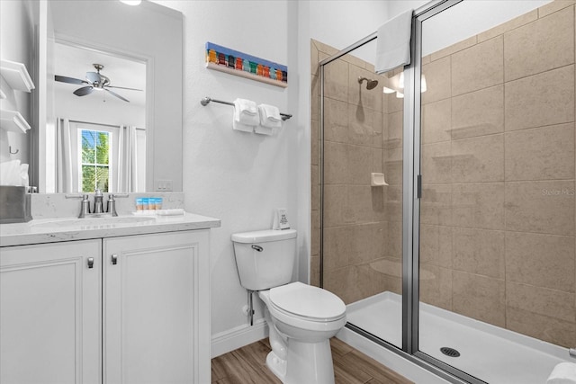 bathroom featuring vanity, walk in shower, ceiling fan, wood-type flooring, and toilet