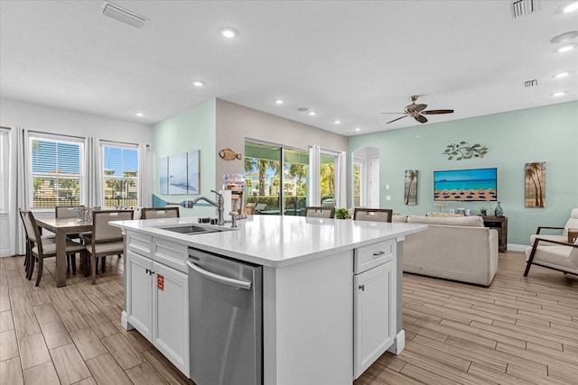 kitchen with stainless steel dishwasher, an island with sink, ceiling fan, sink, and white cabinetry