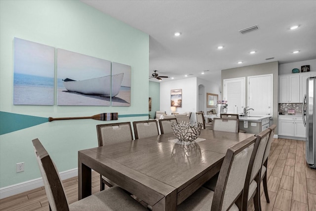 dining space with ceiling fan, sink, and light wood-type flooring