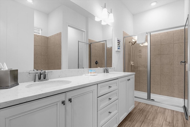 bathroom with an enclosed shower, double sink vanity, and wood-type flooring