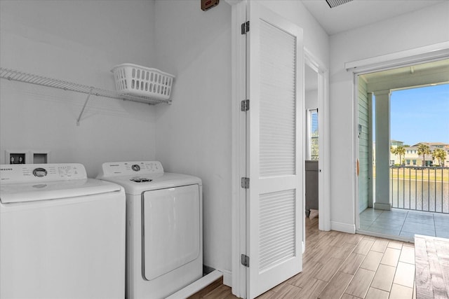 laundry room with independent washer and dryer and light hardwood / wood-style flooring