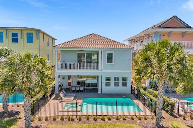 back of property with a fenced in pool, a balcony, and a patio