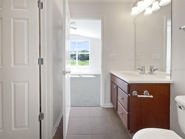 bathroom with tile flooring, toilet, vanity, and vaulted ceiling