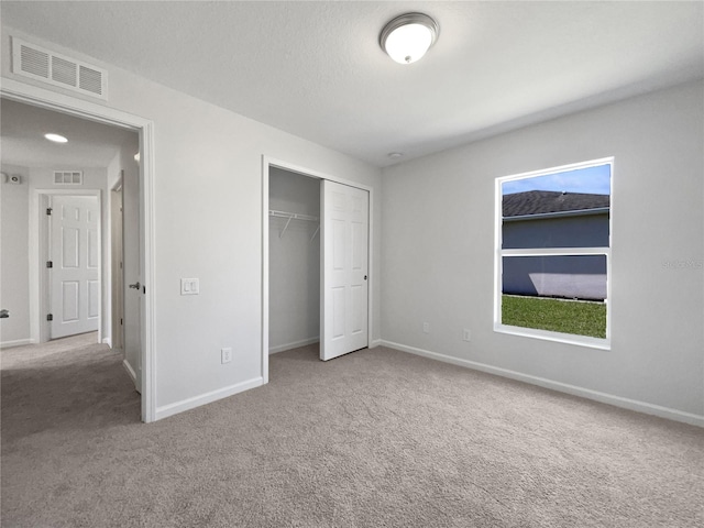 unfurnished bedroom featuring light carpet and a closet