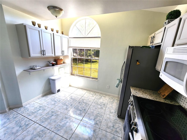 kitchen featuring white cabinets, light stone counters, and light tile floors