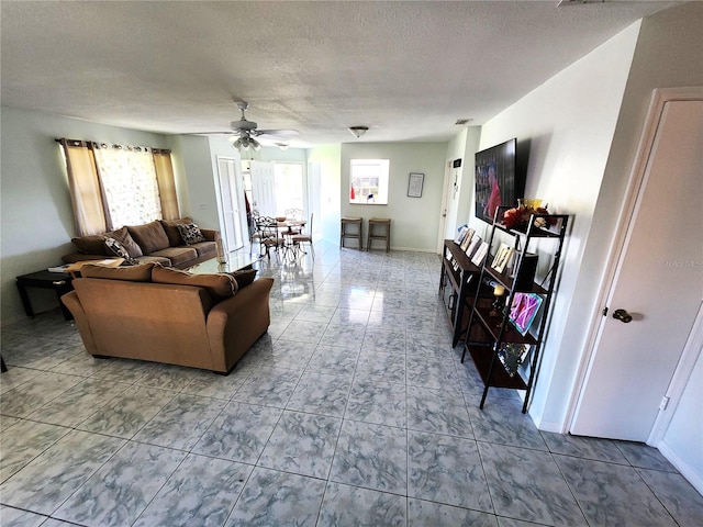 tiled living room with ceiling fan and a textured ceiling