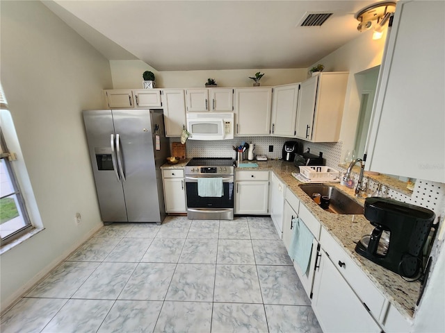 kitchen featuring appliances with stainless steel finishes, a sink, light stone counters, and white cabinets