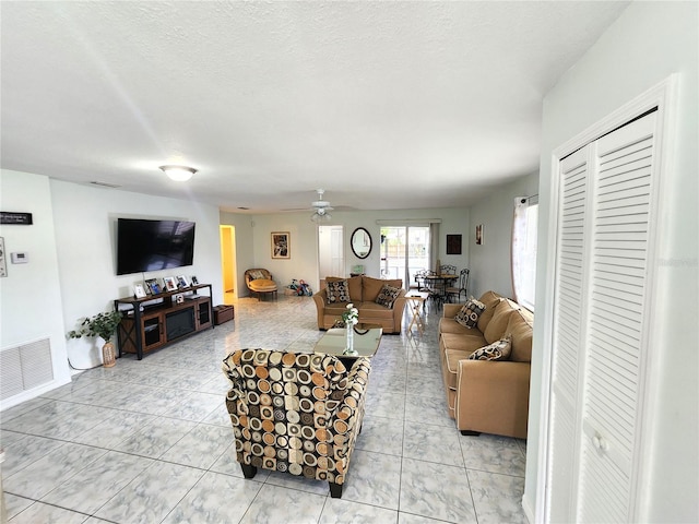 living room featuring visible vents, ceiling fan, and a textured ceiling