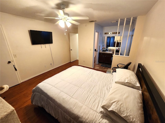 bedroom with ceiling fan, dark wood-style flooring, visible vents, baseboards, and ensuite bath