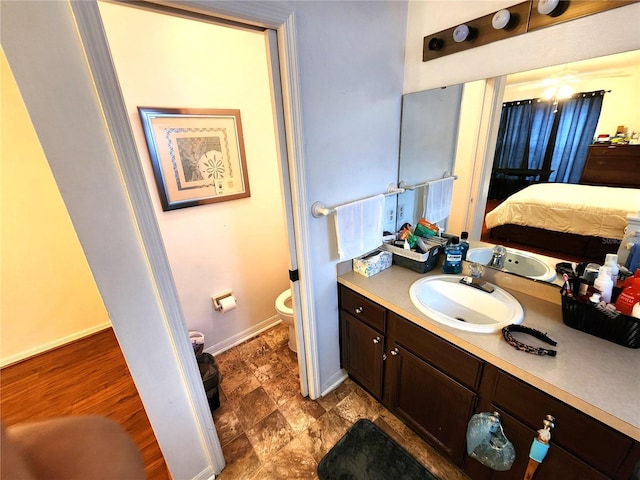 bathroom featuring toilet, vanity, baseboards, and ensuite bathroom