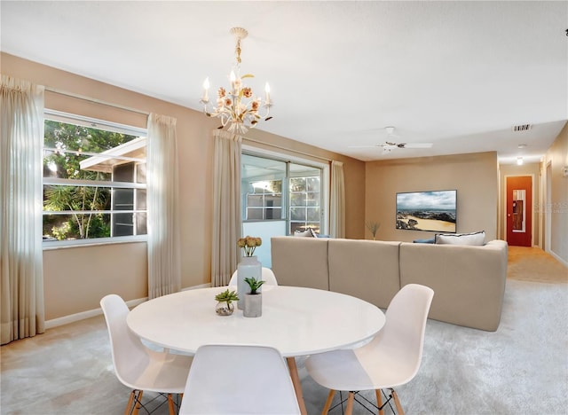 dining space featuring ceiling fan with notable chandelier and light carpet