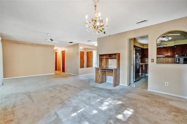 carpeted spare room featuring ceiling fan with notable chandelier