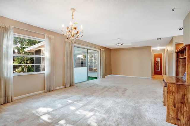 carpeted spare room with ceiling fan with notable chandelier