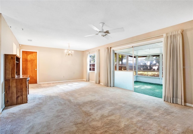 carpeted spare room with ceiling fan with notable chandelier