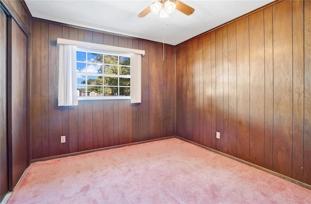 carpeted spare room featuring ceiling fan and wooden walls