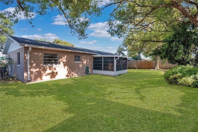 rear view of house with a yard and a sunroom